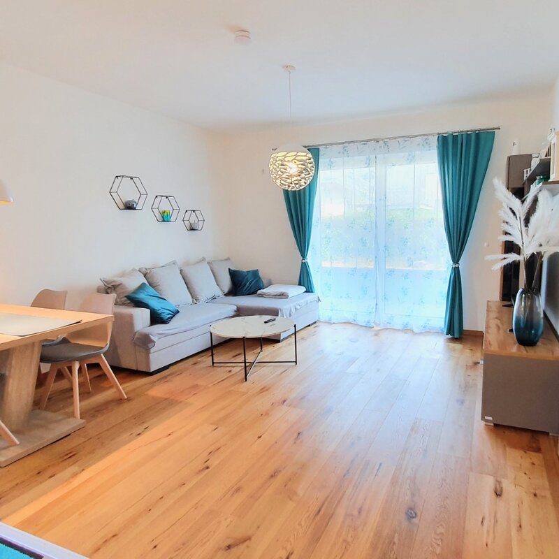 Bright living & dining area with wood floor & balcony access – 2-room short-term rental Braunau am Inn