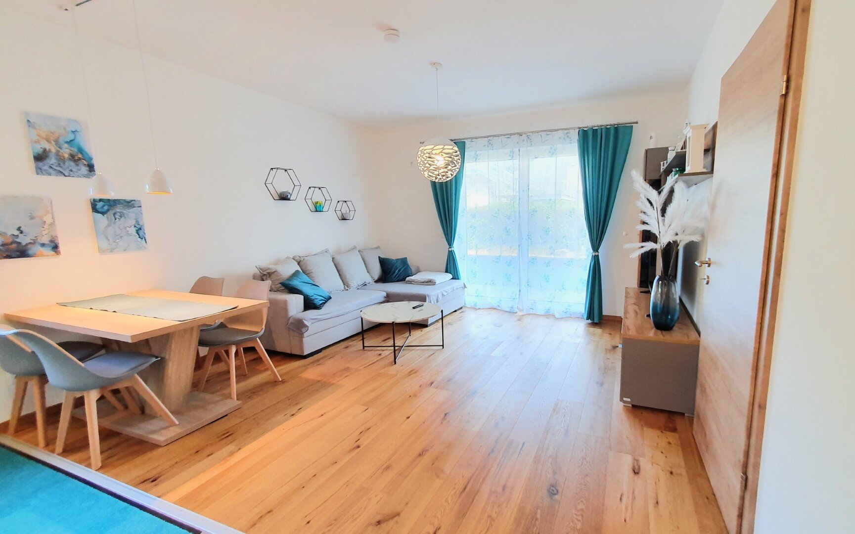 Bright living & dining area with wood floor & balcony access – 2-room short-term rental Braunau am Inn