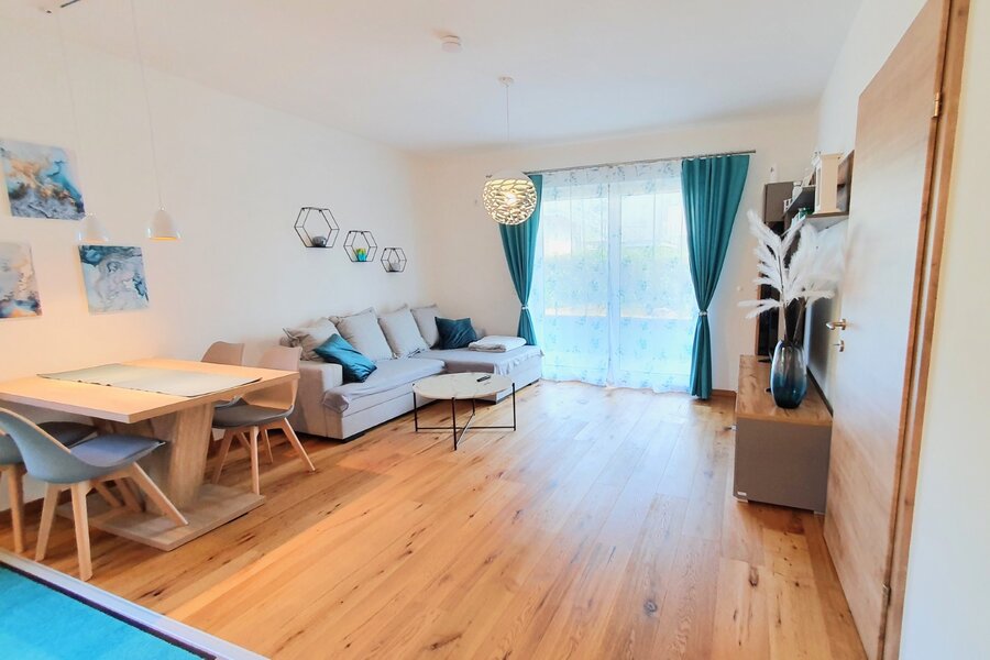 Bright living & dining area with wood floor & balcony access – 2-room short-term rental Braunau am Inn