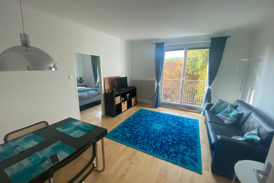 Wohnzimmer mit Couch, TV und Esstisch