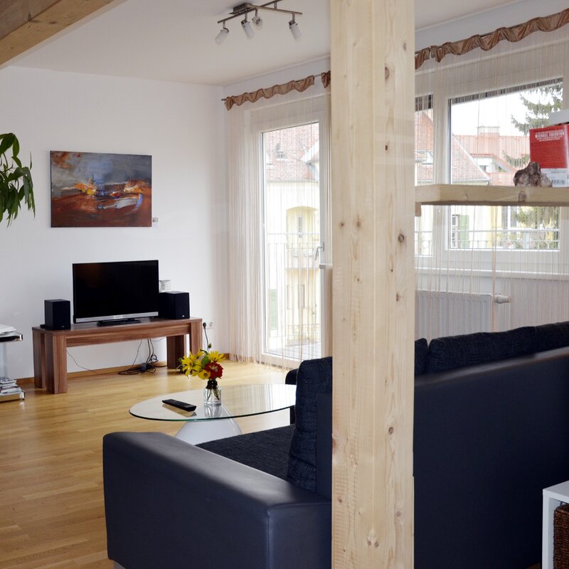 Bright living room with wooden beams & modern TV area – 2-room apartment for short-term rental & temporary housing for 1 to 6 months in Graz