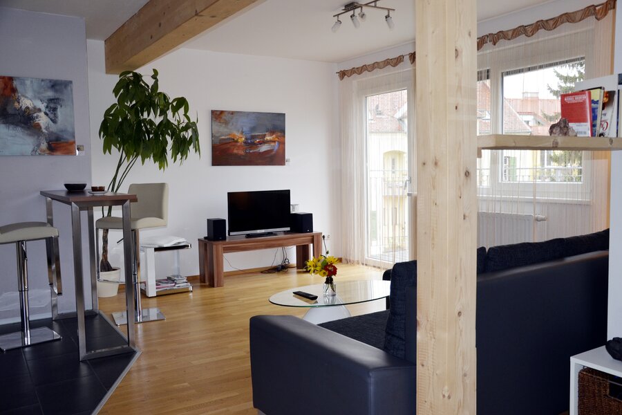 Bright living room with wooden beams & modern TV area – 2-room apartment for short-term rental & temporary housing for 1 to 6 months in Graz