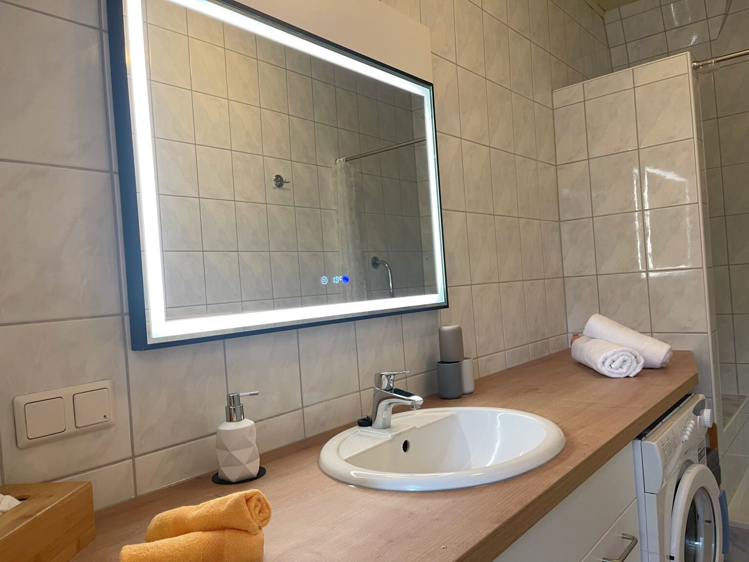 Bathroom with washing machine, shower and large heated and illuminated anti-fog mirror