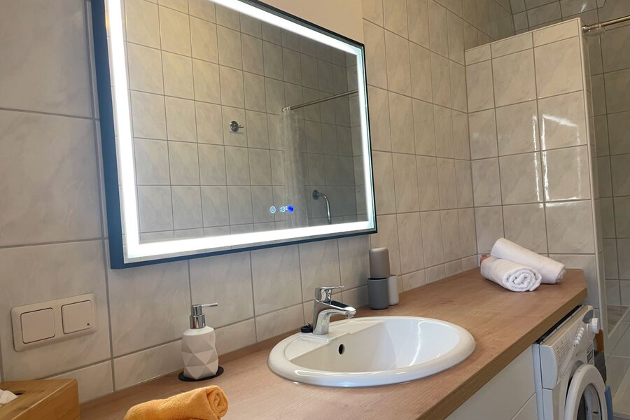 Badezimmer mit Waschmaschine, Dusche und großem beheizten und beleuchteten Anti Beschlagsspiegel