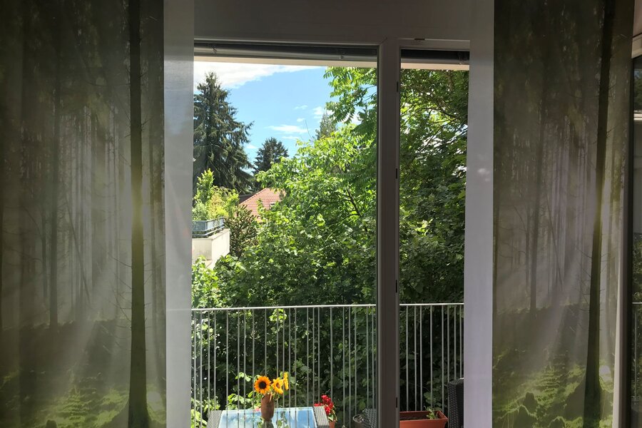 Blick vom Wohnbereich auf die extra große Terasse ins Grüne und auf umliegende Villen