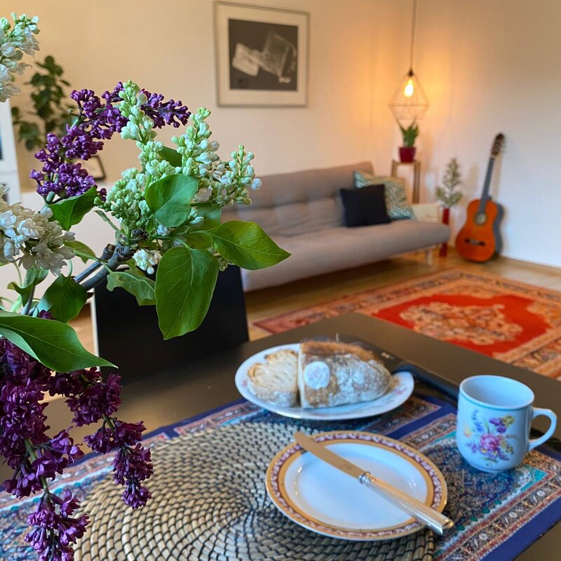 Wohnzimmer mit Flieder, Gitarre & gemütlichem Sofa – 2-Zimmer Wohnung, Kurzzeitmiete Wien, 1 bis 6 Monate