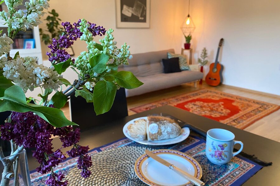 Wohnzimmer mit Flieder, Gitarre & gemütlichem Sofa – 2-Zimmer Wohnung, Kurzzeitmiete Wien, 1 bis 6 Monate