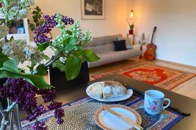 Wohnzimmer mit Flieder, Gitarre & gemütlichem Sofa – 2-Zimmer Wohnung, Kurzzeitmiete Wien, 1 bis 6 Monate