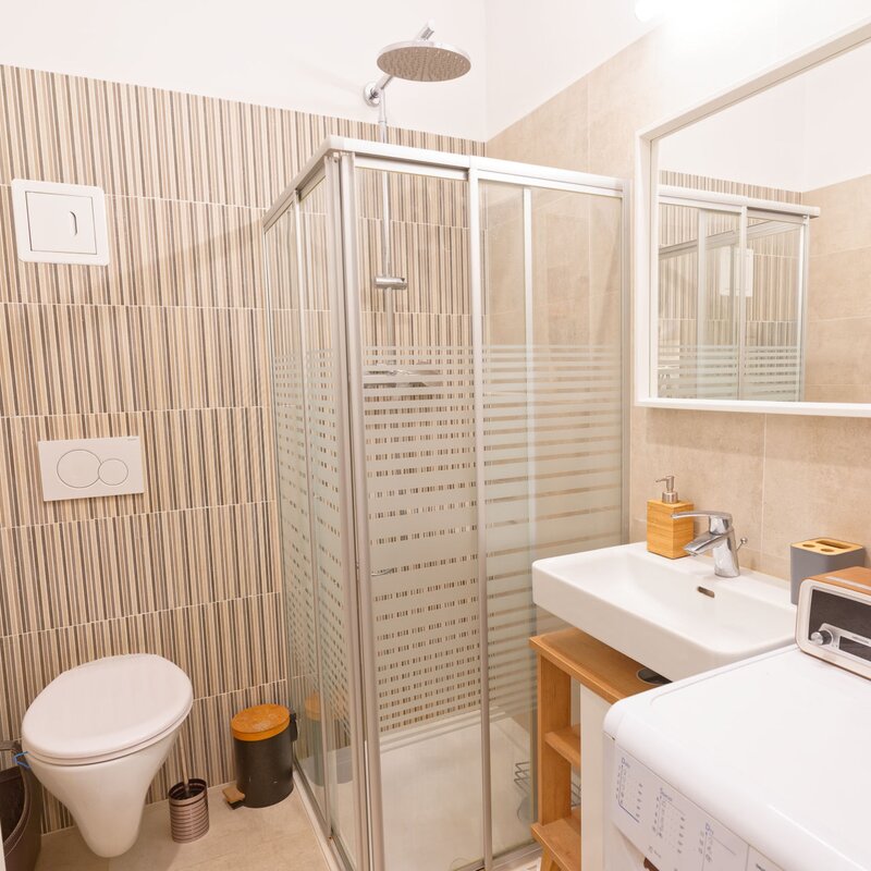 Badezimmer mit Dusche, Toilette, Waschschrank, Spiegel, Waschmaschine, Handtuchwärmer | © Sammer