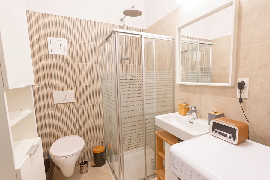 Badezimmer mit Dusche, Toilette, Waschschrank, Spiegel, Waschmaschine, Handtuchwärmer | © Sammer