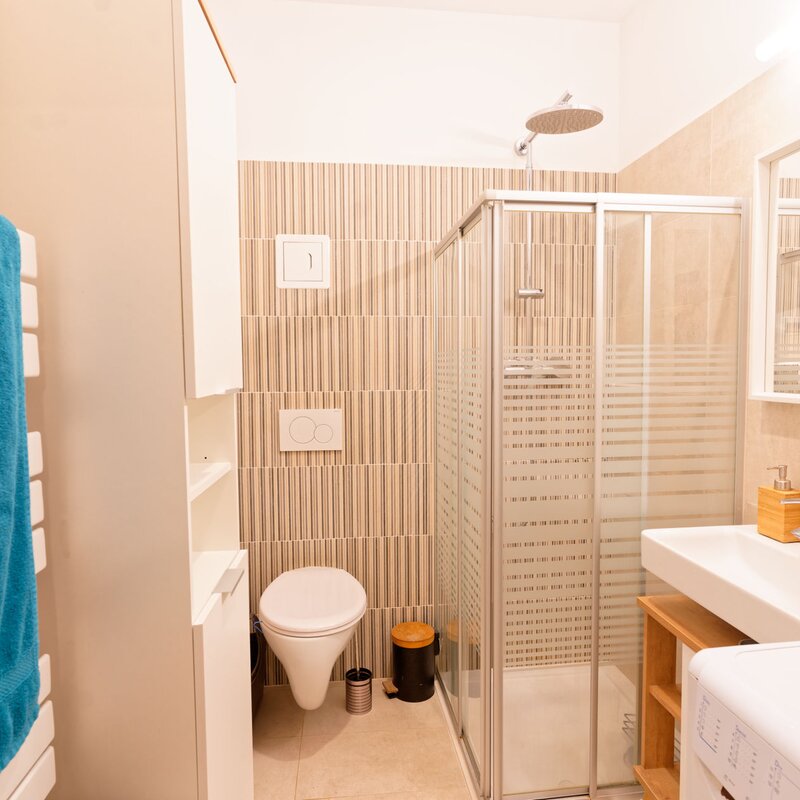 Badezimmer mit Dusche, Toilette, Waschschrank, Spiegel, Waschmaschine, Handtuchwärmer | © Sammer