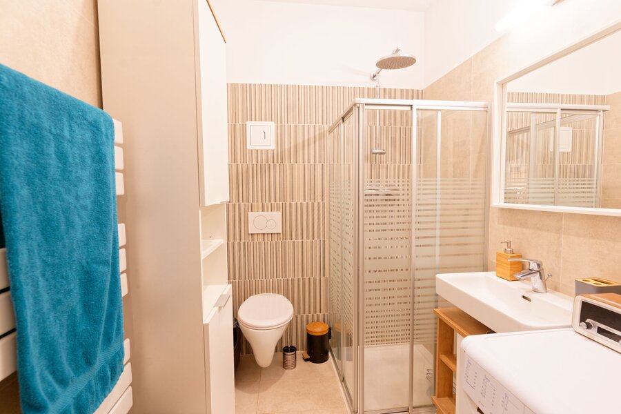 Badezimmer mit Dusche, Toilette, Waschschrank, Spiegel, Waschmaschine, Handtuchwärmer | © Sammer