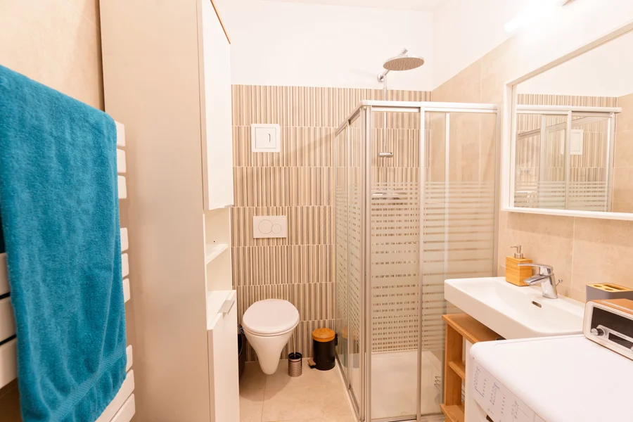 Badezimmer mit Dusche, Toilette, Waschschrank, Spiegel, Waschmaschine, Handtuchwärmer | © Sammer