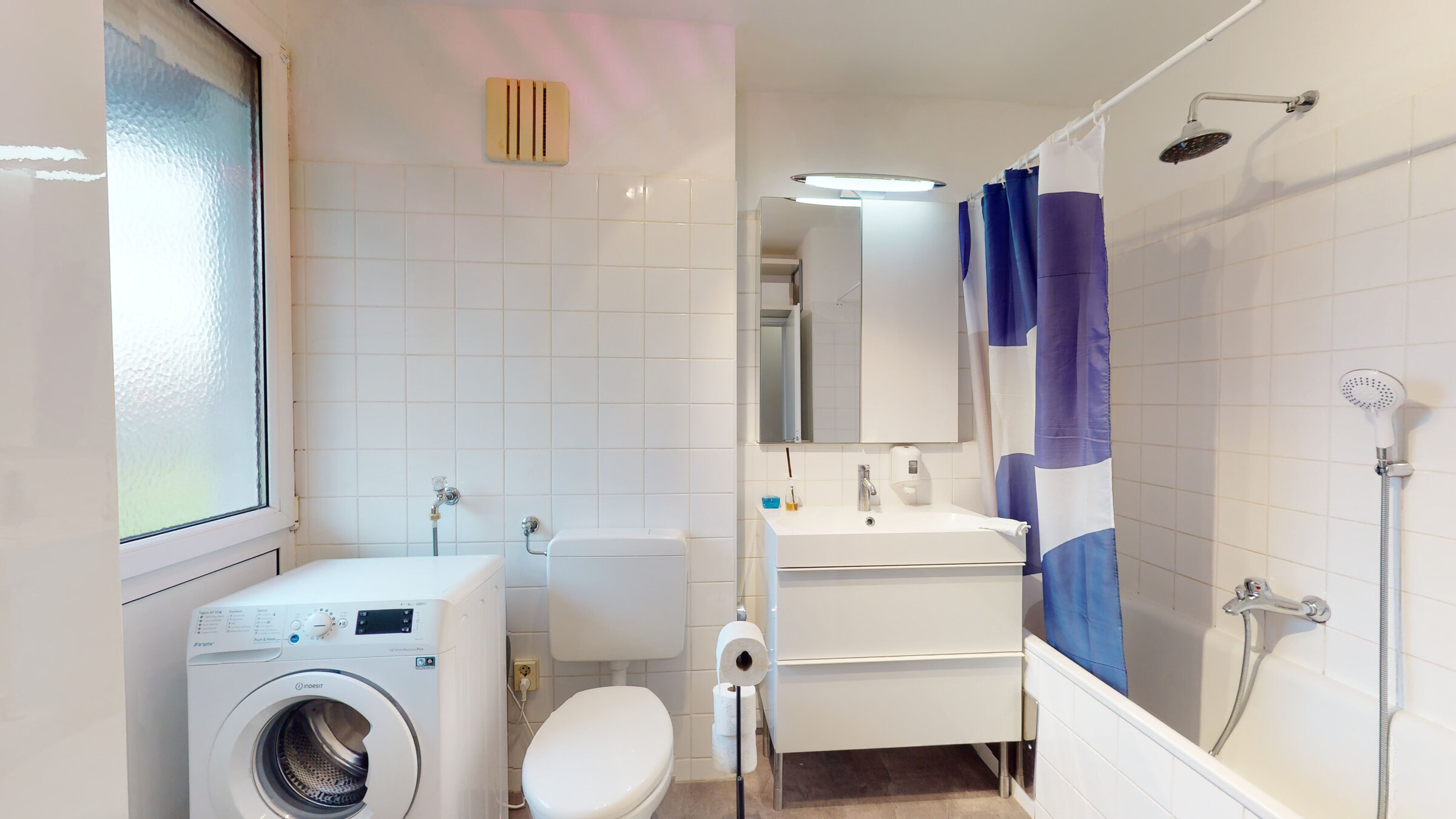 Badezimmer mit Wanne und Duschbereich, Waschmaschine. 