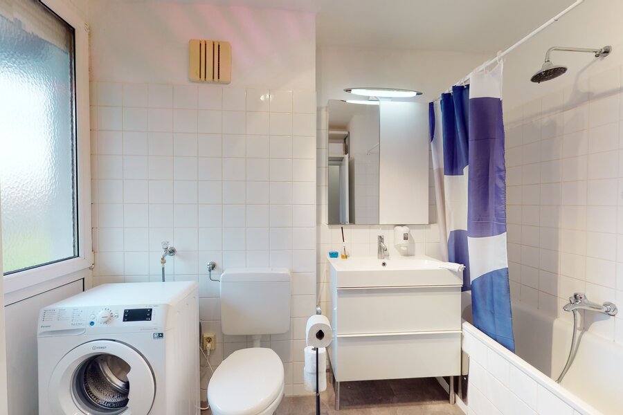 Badezimmer mit Wanne und Duschbereich, Waschmaschine. 