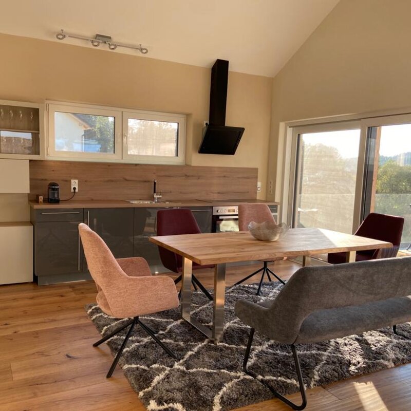 Open living & dining area with wooden table and modern kitchen – house for short-term rental & temporary housing for 1 to 6 months in Vasoldsberg