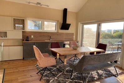 Open living & dining area with wooden table and modern kitchen – house for short-term rental & temporary housing for 1 to 6 months in Vasoldsberg