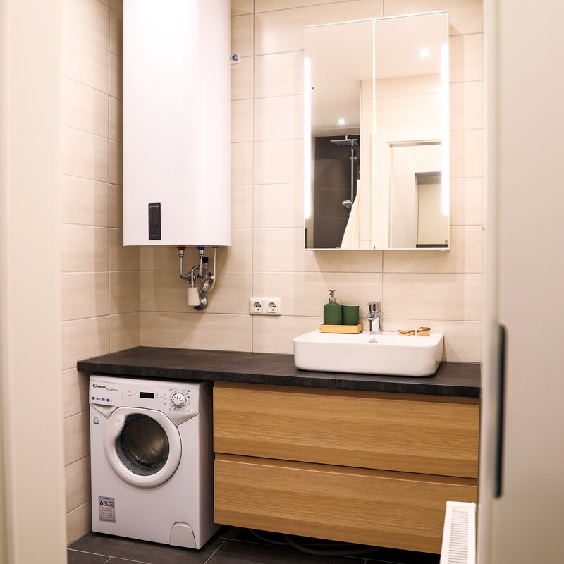 Badezimmer mit Waschmaschine und geräumiger Kommode
