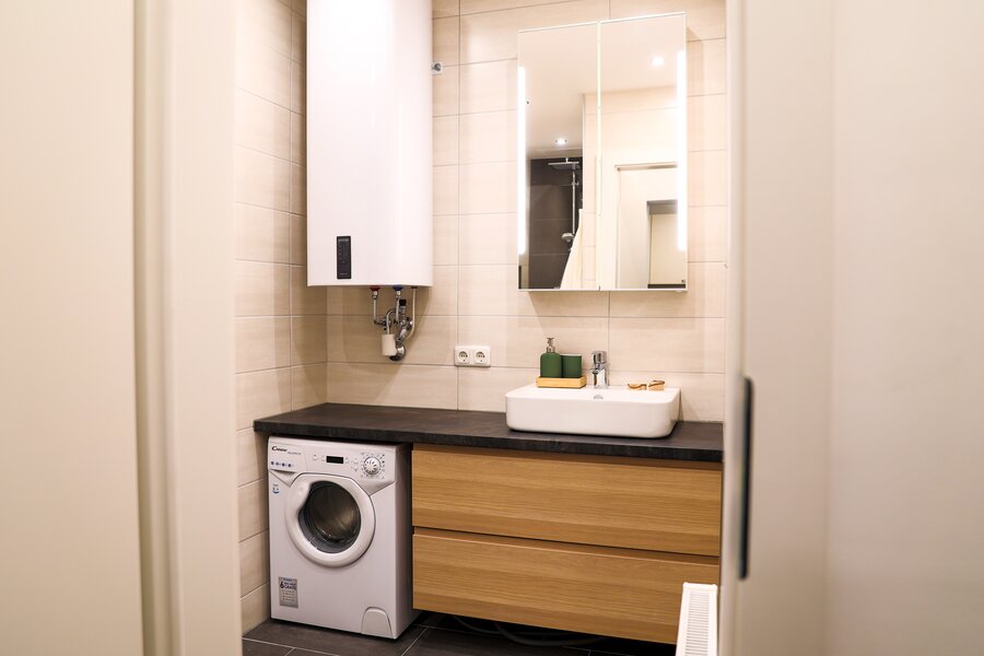 Badezimmer mit Waschmaschine und geräumiger Kommode