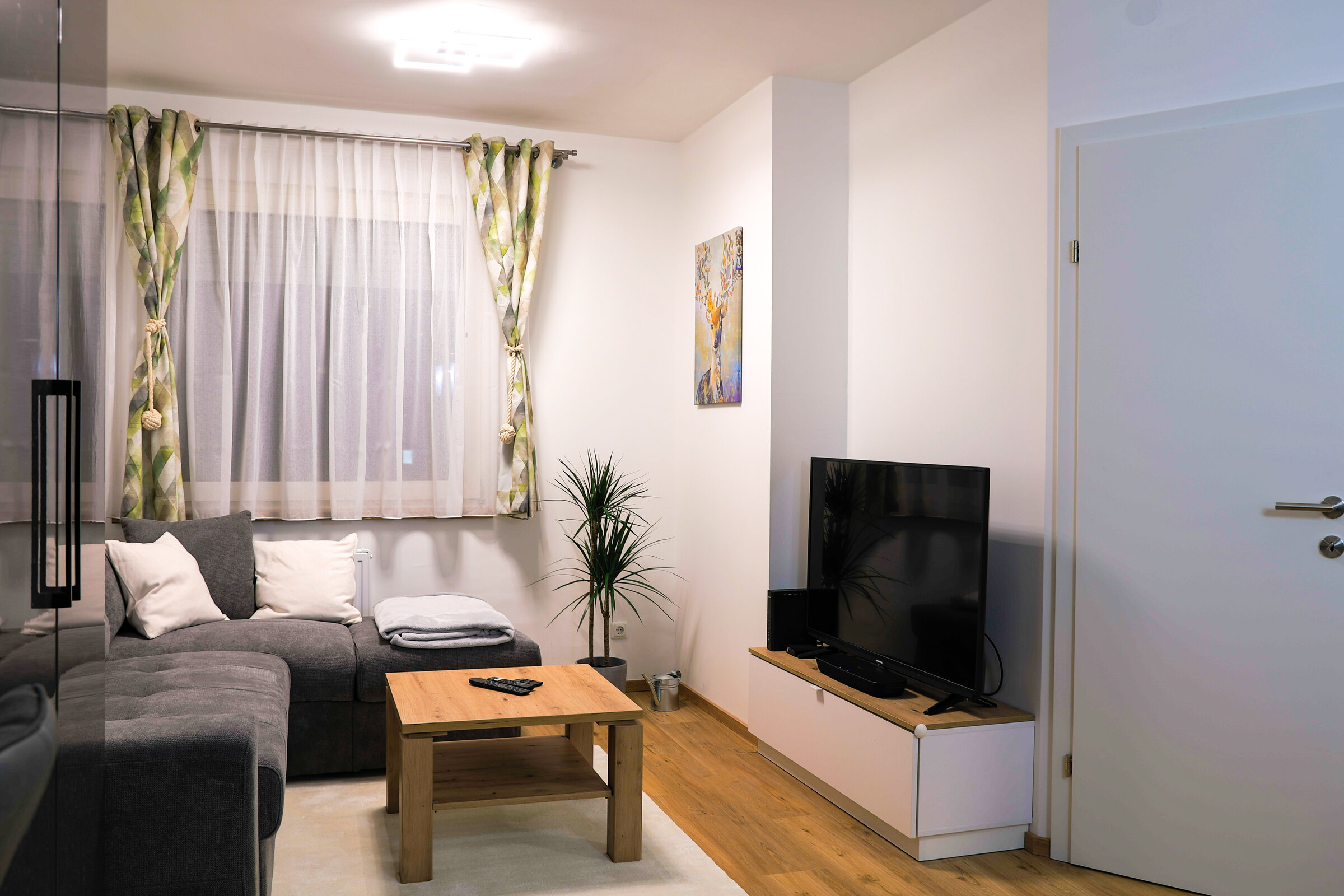 Wohnzimmer mit sehr gemütlicher Couch, TV und Soundbar