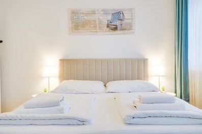 Helles Schlafzimmer mit Doppelbett & Stranddekor – 1-Zimmer Apartment zur Kurzzeitmiete, Wohnen auf Zeit 1 bis 6 Monate, Innsbruck