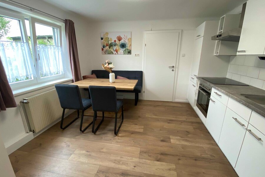 Wohnküche mit bequemer Sitzbank mit Blick in den Garten und TV.