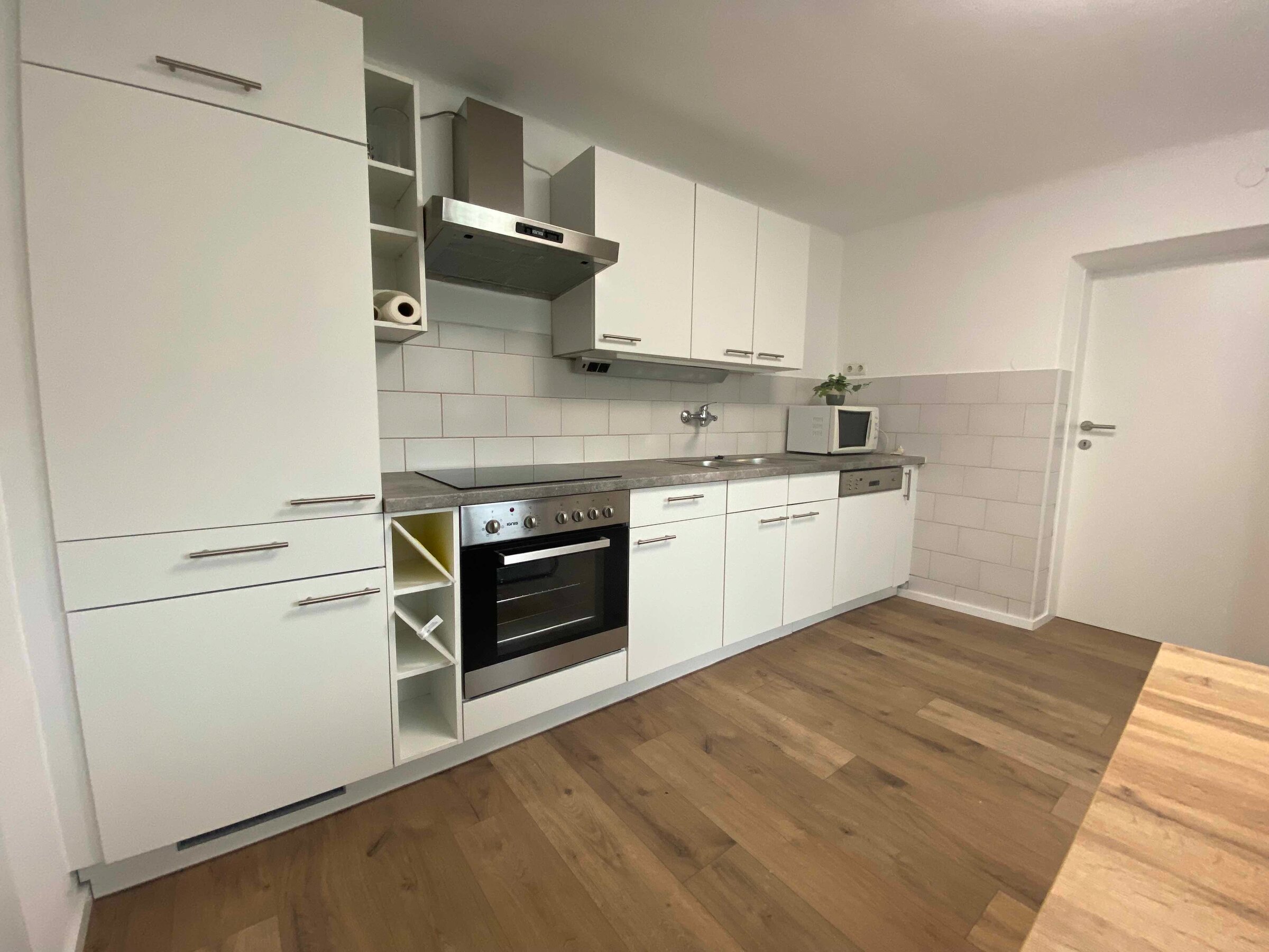 Küchenzeile mit Einbaukühlschrank, Herd u Backofen und Microwelle.