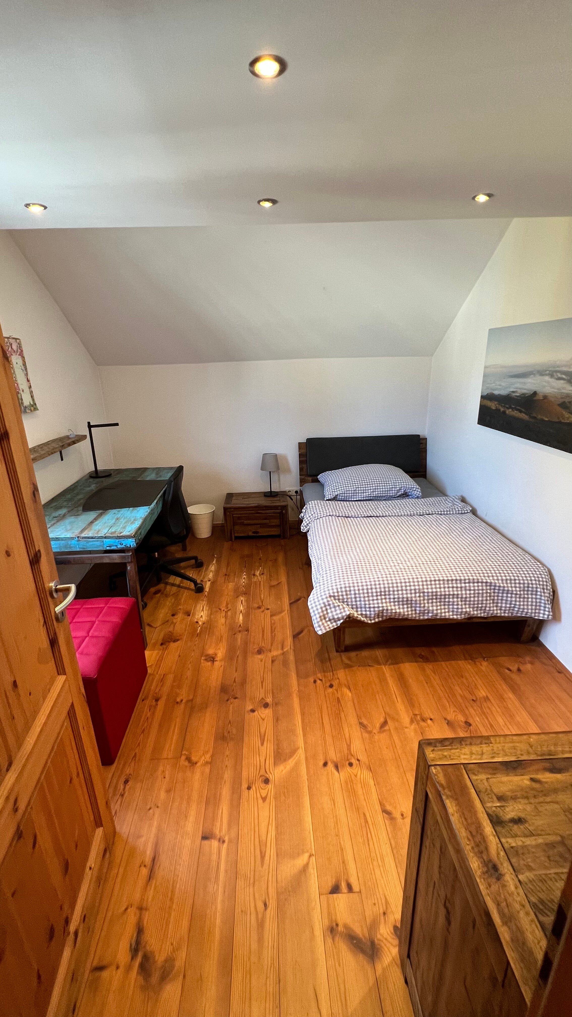 This inviting single room combines cosiness with functionality and is equipped with a comfortable single bed and a desk. It is the perfect retreat for guests looking for a quiet work area or a cozy reading spot. A small chest of drawers provides practical storage space for personal items. The well-thought-out furnishings create an atmosphere that invites both productivity and relaxation.