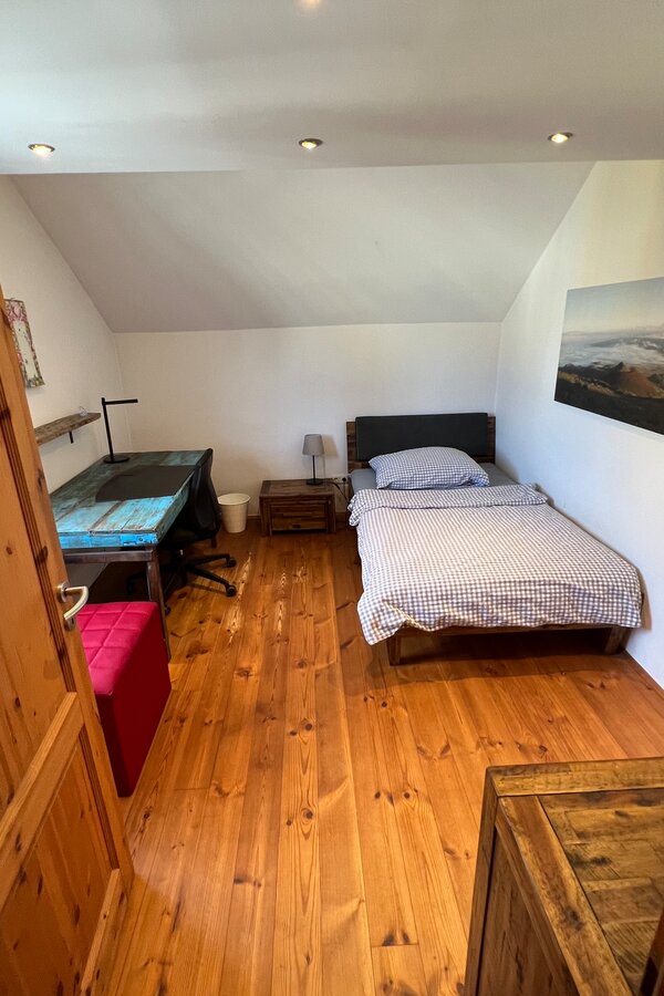 This inviting single room combines cosiness with functionality and is equipped with a comfortable single bed and a desk. It is the perfect retreat for guests looking for a quiet work area or a cozy reading spot. A small chest of drawers provides practical storage space for personal items. The well-thought-out furnishings create an atmosphere that invites both productivity and relaxation.