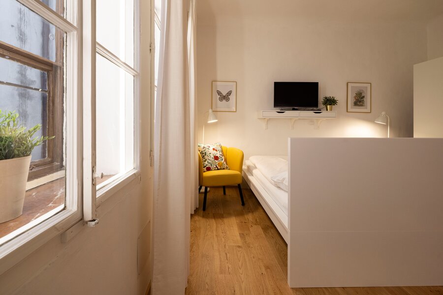 Helles 1-Zimmer Apartment mit Holzboden & gelbem Sessel – Wohnen auf Zeit & Kurzzeitmiete Salzburg, 1 bis 6 Monate