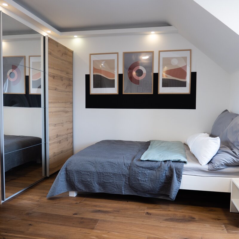 Modern bedroom with wood floors & mirrored wardrobe – 3-room apartment, short-term rental Vienna, 1–6 months