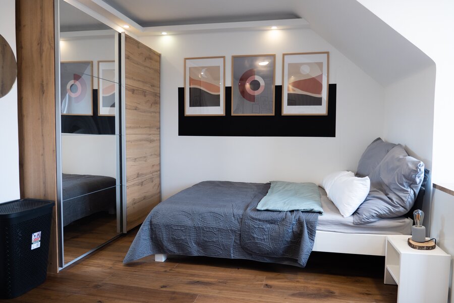 Modern bedroom with wood floors & mirrored wardrobe – 3-room apartment, short-term rental Vienna, 1–6 months