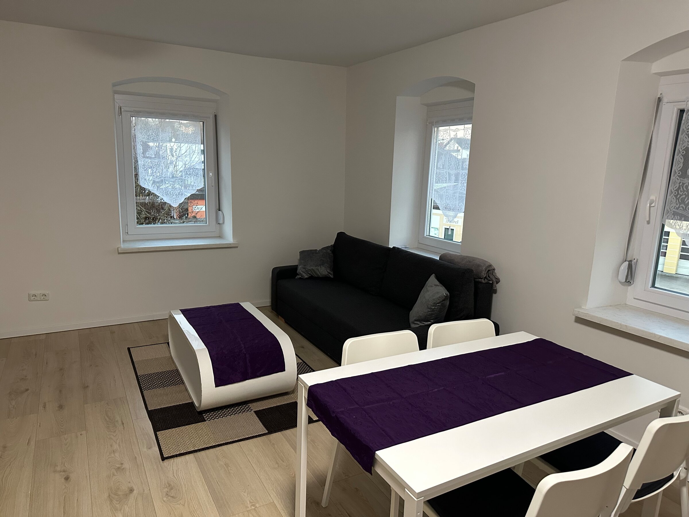 Heller Wohn-Essbereich mit schwarzem Sofa & weißem Esstisch – 3-Zimmer Wohnung, Kurzzeitmiete Niederthalheim, Wohnen auf Zeit 1–6 Monate