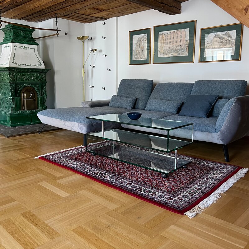 Wohnzimmer mit grünem Kachelofen & Holzbalkendecke – 3-Zimmer Wohnung, Kurzzeitmiete & Wohnen auf Zeit für 1 bis 6 Monate, Salzburg