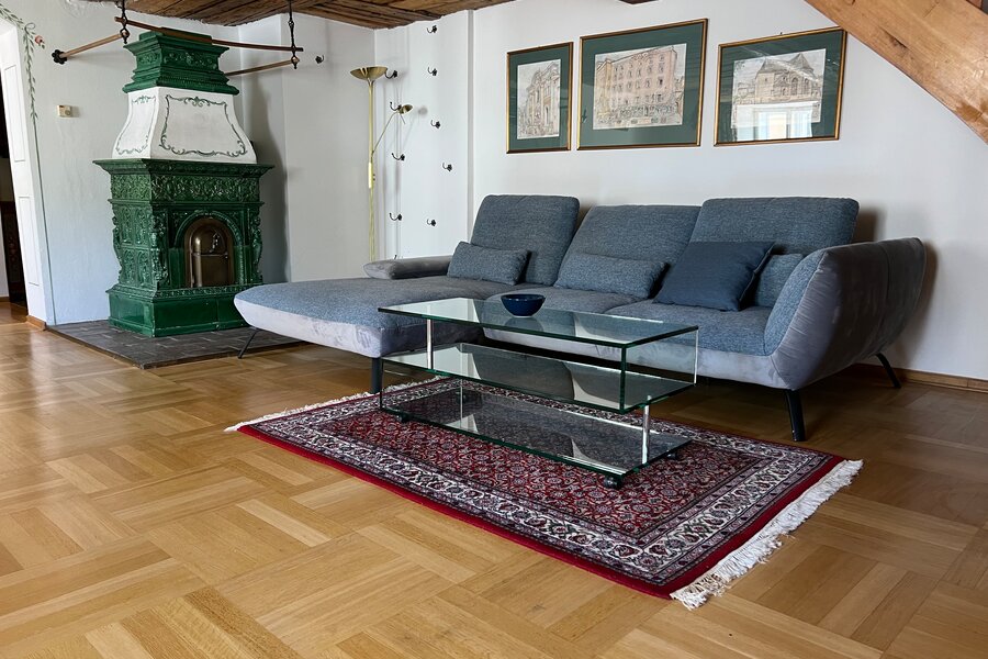Wohnzimmer mit grünem Kachelofen & Holzbalkendecke – 3-Zimmer Wohnung, Kurzzeitmiete & Wohnen auf Zeit für 1 bis 6 Monate, Salzburg