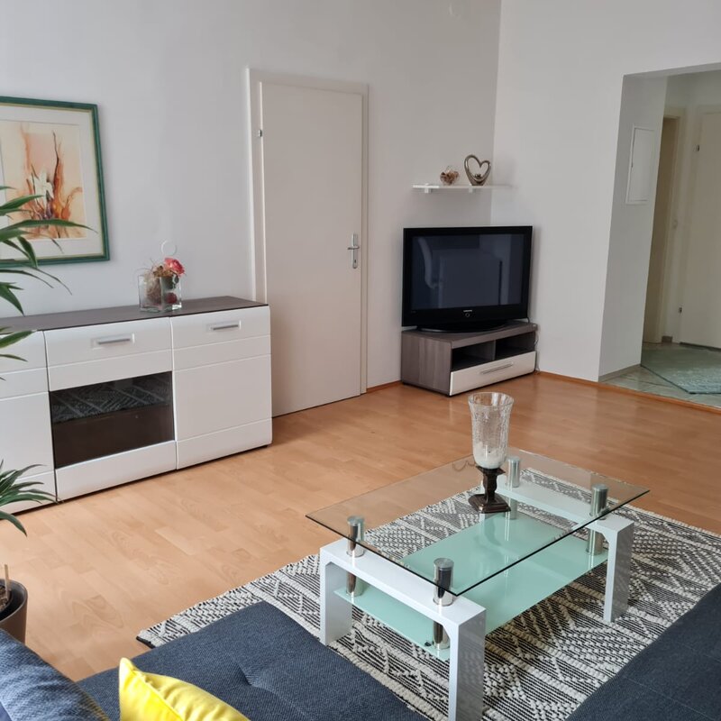 Helles Wohnzimmer mit Glasstisch & TV – 2-Zimmer Wohnung, Kurzzeitmiete & Wohnen auf Zeit für 1 bis 6 Monate in Graz