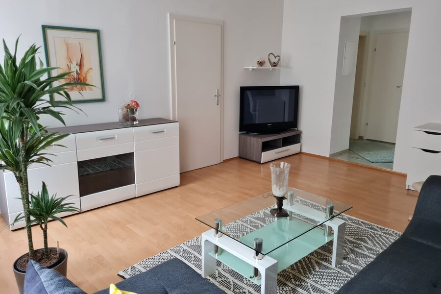 Helles Wohnzimmer mit Glasstisch & TV – 2-Zimmer Wohnung, Kurzzeitmiete & Wohnen auf Zeit für 1 bis 6 Monate in Graz