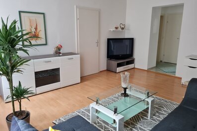 Helles Wohnzimmer mit Glasstisch & TV – 2-Zimmer Wohnung, Kurzzeitmiete & Wohnen auf Zeit für 1 bis 6 Monate in Graz