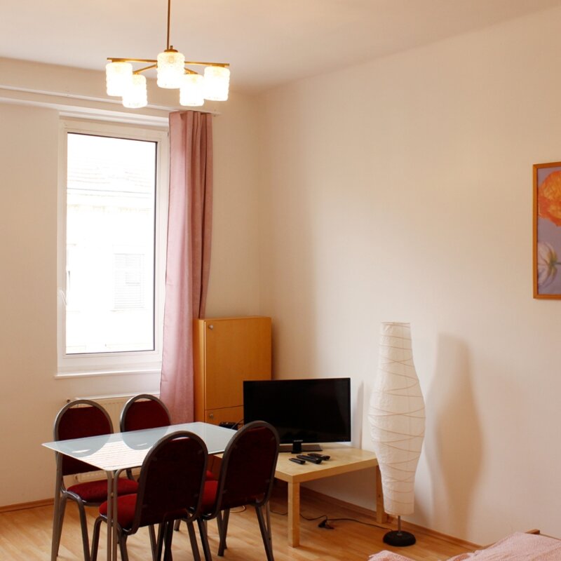 Helles Wohnzimmer mit Esstisch & TV – 1-Zimmer Wohnung zur Kurzzeitmiete, Wohnen auf Zeit für 1 bis 6 Monate in Wien