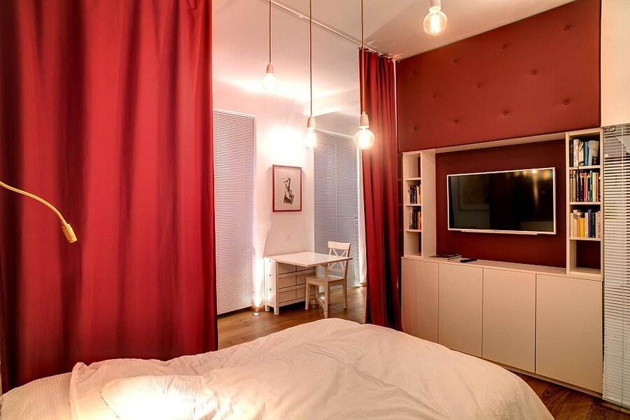 Stilvolles Schlafzimmer mit rotem Akzent & TV – 1-Zimmer Wohnung zur Kurzzeitmiete, Wohnen auf Zeit 1 bis 6 Monate, Wien