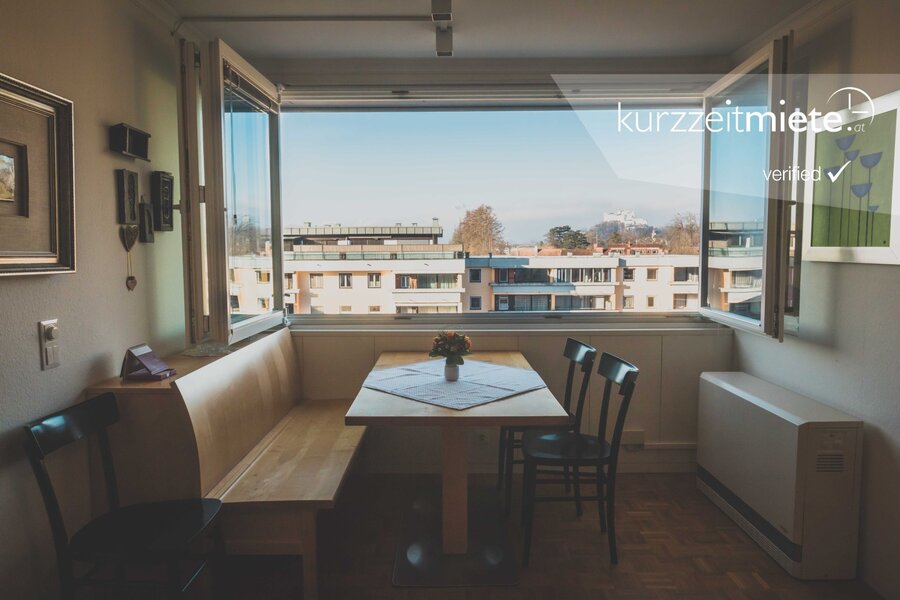 Dining area with large window & city view – 2-room apartment, short-term rental & temporary housing for 1 to 6 months in Aigen