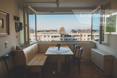 Dining area with large window & city view – 2-room apartment, short-term rental & temporary housing for 1 to 6 months in Aigen