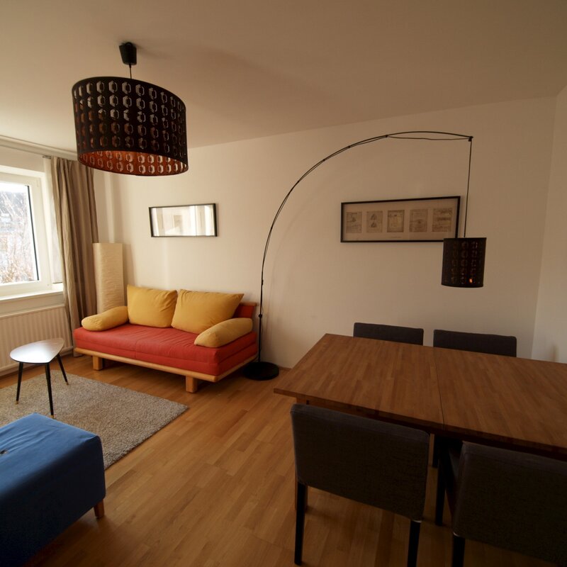 Wohnzimmer mit Ausziehcouch und Esstisch.