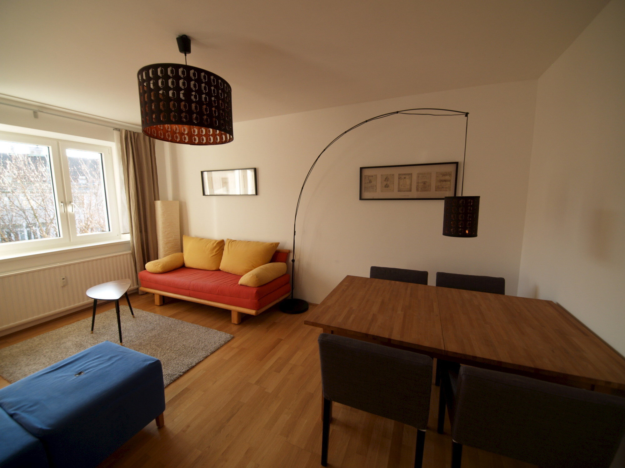 Wohnzimmer mit Ausziehcouch und Esstisch.