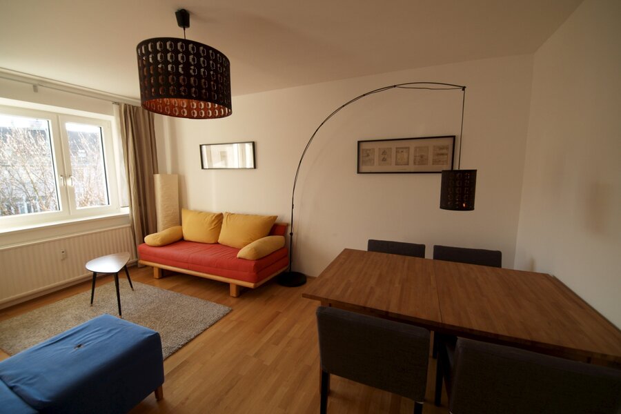 Wohnzimmer mit Ausziehcouch und Esstisch.