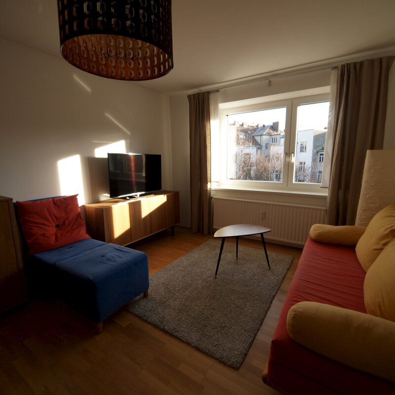 Wohnzimmer mit Ausziehcouch und Esstisch.