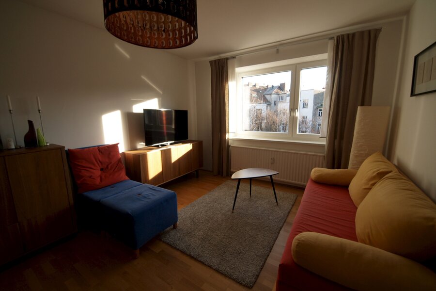 Wohnzimmer mit Ausziehcouch und Esstisch.