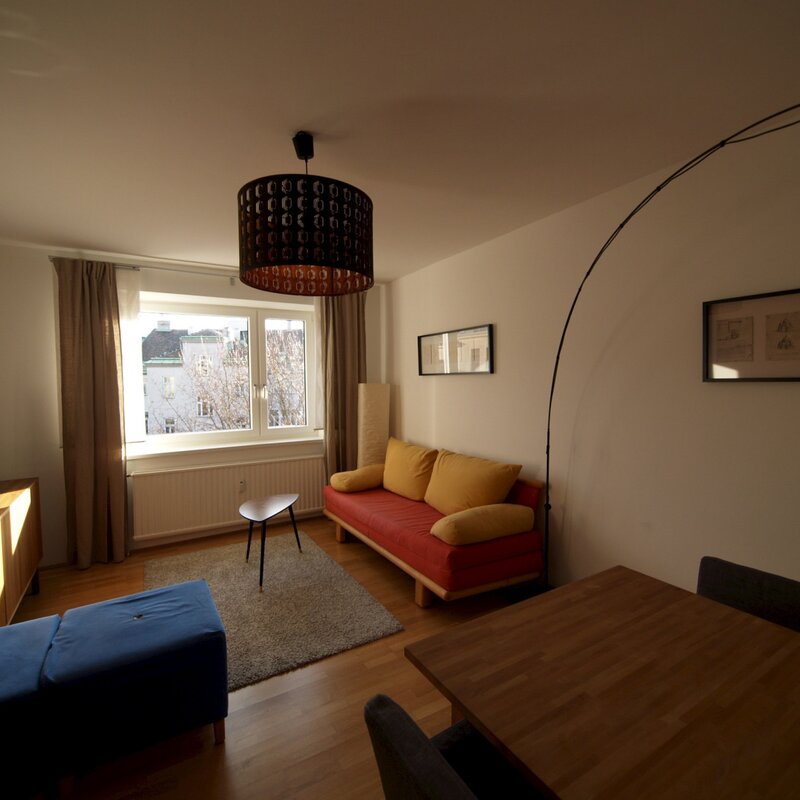 Wohnzimmer mit Ausziehcouch und Esstisch.