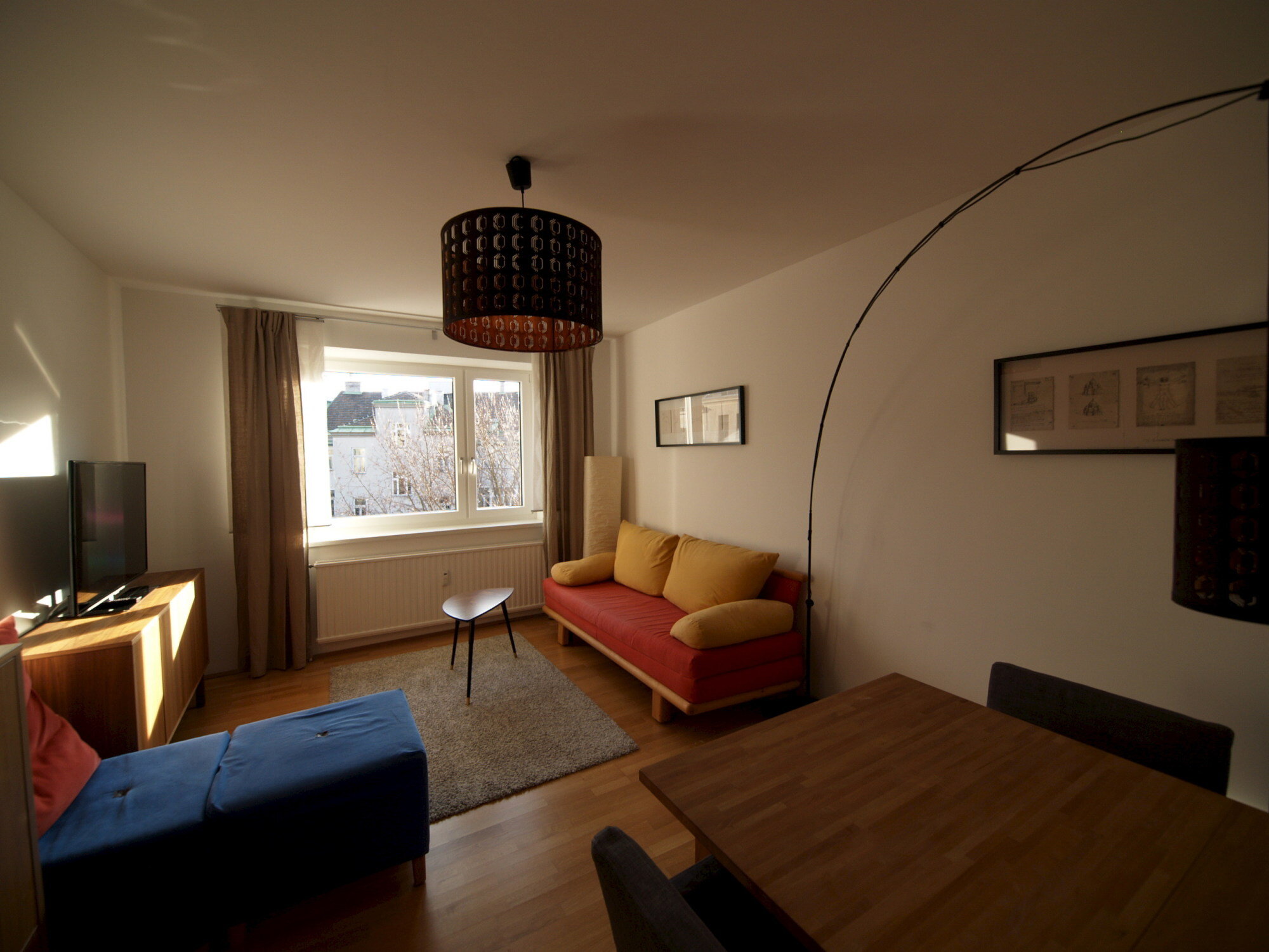 Wohnzimmer mit Ausziehcouch und Esstisch.