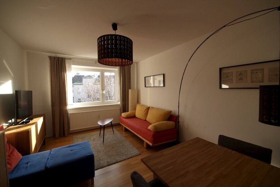 Wohnzimmer mit Ausziehcouch und Esstisch.